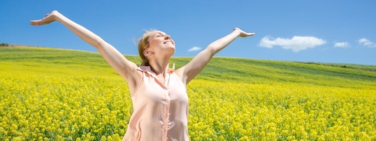 woman standing in field of flowers feeling the sunshine